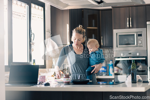 Image of Happy mother and little infant baby boy together making pancakes for breakfast in domestic kitchen. Family, lifestyle, domestic life, food, healthy eating and people concept.