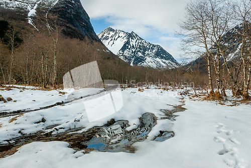 Image of snowy mountain peak with snow reflecting in water in the foregro