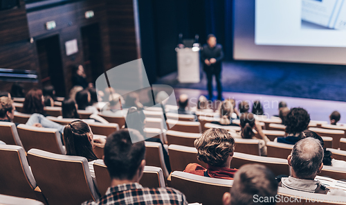 Image of Speaker giving a talk in conference hall at business event. Rear view of unrecognizable people in audience at the conference hall. Business and entrepreneurship concept.