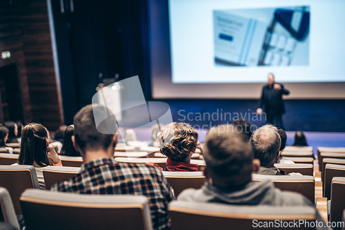 Image of Speaker giving a talk in conference hall at business event. Rear view of unrecognizable people in audience at the conference hall. Business and entrepreneurship concept.