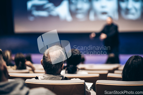 Image of Speaker giving a talk in conference hall at business event. Rear view of unrecognizable people in audience at the conference hall. Business and entrepreneurship concept.