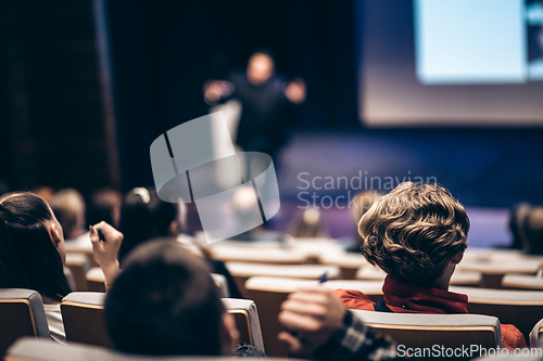 Image of Speaker giving a talk in conference hall at business event. Rear view of unrecognizable people in audience at the conference hall. Business and entrepreneurship concept.