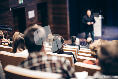 Image of Speaker giving a talk in conference hall at business event. Rear view of unrecognizable people in audience at the conference hall. Business and entrepreneurship concept.