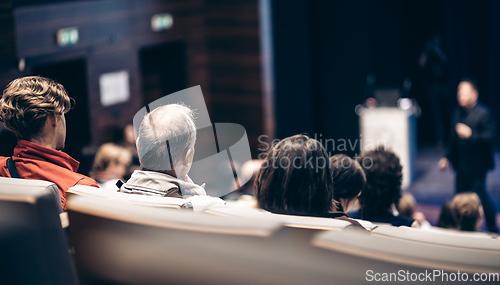 Image of Speaker giving a talk in conference hall at business event. Rear view of unrecognizable people in audience at the conference hall. Business and entrepreneurship concept.