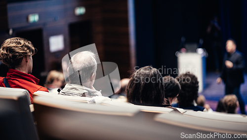 Image of Speaker giving a talk in conference hall at business event. Rear view of unrecognizable people in audience at the conference hall. Business and entrepreneurship concept.