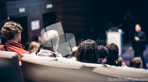 Image of Speaker giving a talk in conference hall at business event. Rear view of unrecognizable people in audience at the conference hall. Business and entrepreneurship concept.