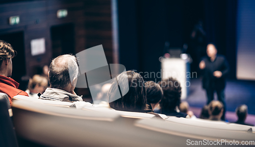 Image of Speaker giving a talk in conference hall at business event. Rear view of unrecognizable people in audience at the conference hall. Business and entrepreneurship concept.