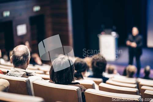 Image of Speaker giving a talk in conference hall at business event. Rear view of unrecognizable people in audience at the conference hall. Business and entrepreneurship concept.