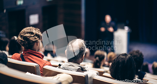 Image of Speaker giving a talk in conference hall at business event. Rear view of unrecognizable people in audience at the conference hall. Business and entrepreneurship concept.