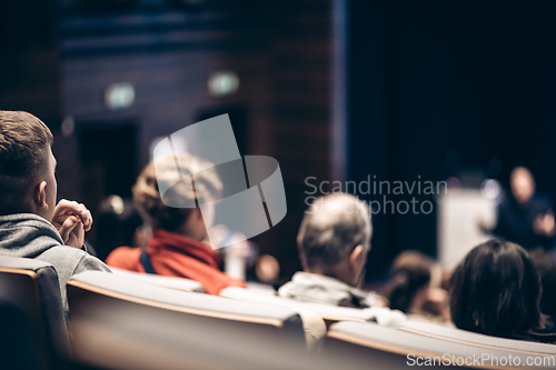 Image of Speaker giving a talk in conference hall at business event. Rear view of unrecognizable people in audience at the conference hall. Business and entrepreneurship concept.