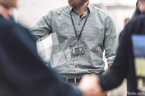 Image of Business people shaking hands while meeting and exchanging business promotional materials and brochures on business meeting on trade-show. Business discussion talking deal concept.