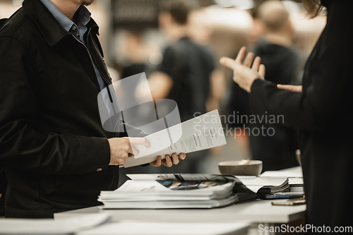 Image of Business people exchanging business promotional materials and brochure on business meeting on trade-show. Business discussion talking deal concept.