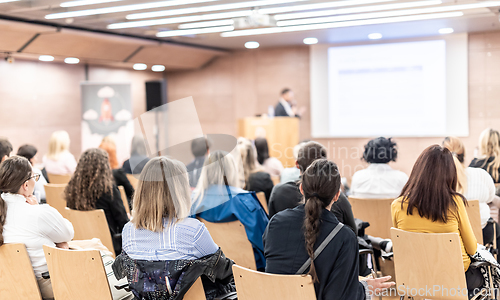 Image of Speaker giving a talk in conference hall at business event. Rear view of unrecognizable people in audience at the conference hall. Business and entrepreneurship concept.