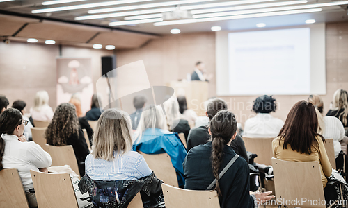 Image of Speaker giving a talk in conference hall at business event. Rear view of unrecognizable people in audience at the conference hall. Business and entrepreneurship concept.