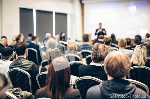 Image of Speaker giving a talk in conference hall at business event. Rear view of unrecognizable people in audience at the conference hall. Business and entrepreneurship concept.