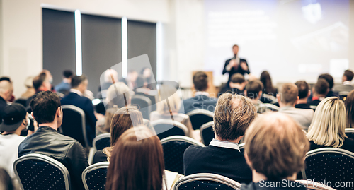 Image of Speaker giving a talk in conference hall at business event. Rear view of unrecognizable people in audience at the conference hall. Business and entrepreneurship concept.