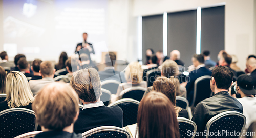 Image of Speaker giving a talk in conference hall at business event. Rear view of unrecognizable people in audience at the conference hall. Business and entrepreneurship concept.