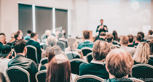 Image of Speaker giving a talk in conference hall at business event. Rear view of unrecognizable people in audience at the conference hall. Business and entrepreneurship concept.