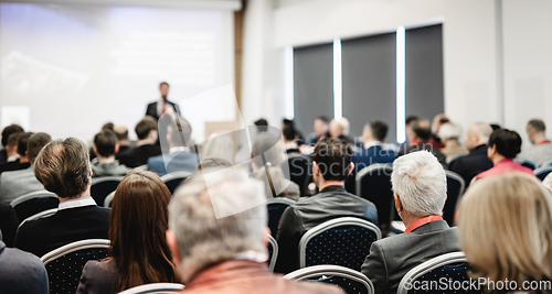 Image of Speaker giving a talk in conference hall at business event. Rear view of unrecognizable people in audience at the conference hall. Business and entrepreneurship concept.