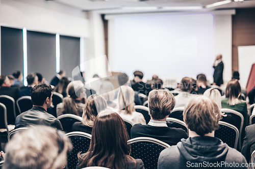 Image of Speaker giving a talk in conference hall at business event. Rear view of unrecognizable people in audience at the conference hall. Business and entrepreneurship concept.