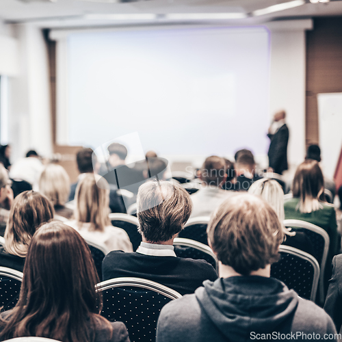 Image of Speaker giving a talk in conference hall at business event. Rear view of unrecognizable people in audience at the conference hall. Business and entrepreneurship concept.