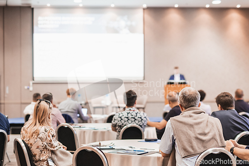 Image of Speaker giving a talk in conference hall at business event. Rear view of unrecognizable people in audience at the conference hall. Business and entrepreneurship concept.