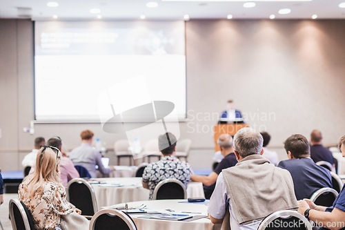 Image of Speaker giving a talk in conference hall at business event. Rear view of unrecognizable people in audience at the conference hall. Business and entrepreneurship concept.