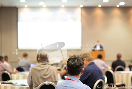 Image of Speaker giving a talk in conference hall at business event. Rear view of unrecognizable people in audience at the conference hall. Business and entrepreneurship concept.