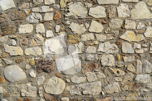 Image of Old wall texture of various stones lit by the sun