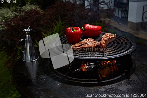 Image of Tomahawk rib beef steak and T-bone on hot black grill.