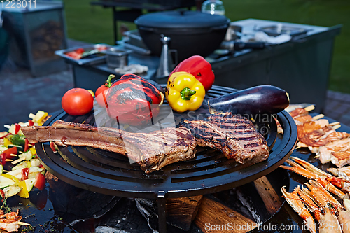 Image of Tomahawk rib beef steak and T-bone on hot black grill.