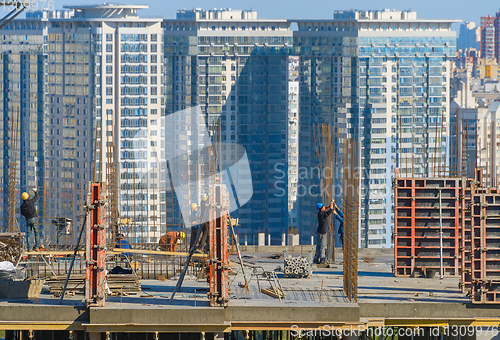 Image of Construction workers work top building