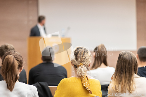 Image of Speaker giving a talk in conference hall at business event. Rear view of unrecognizable people in audience at the conference hall. Business and entrepreneurship concept.