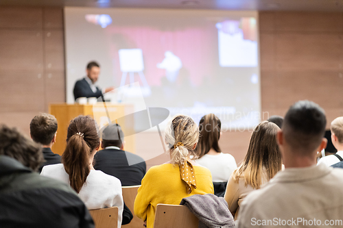 Image of Speaker giving a talk in conference hall at business event. Rear view of unrecognizable people in audience at the conference hall. Business and entrepreneurship concept.