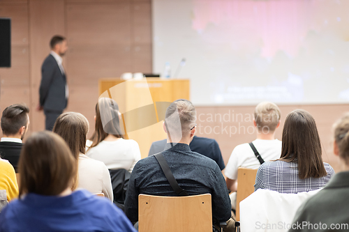 Image of Speaker giving a talk in conference hall at business event. Rear view of unrecognizable people in audience at the conference hall. Business and entrepreneurship concept.