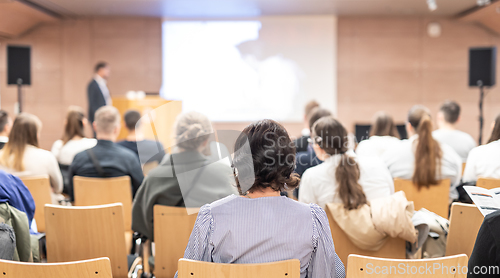 Image of Speaker giving a talk in conference hall at business event. Rear view of unrecognizable people in audience at the conference hall. Business and entrepreneurship concept.