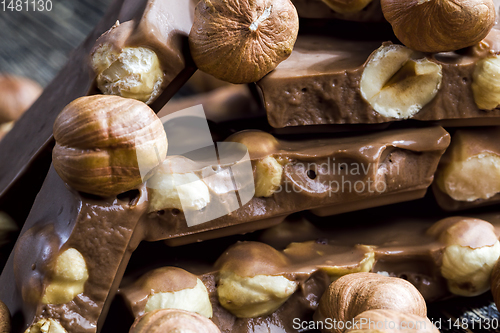 Image of bitter real chocolate, photographed close-up with whole hazelnuts inside and next to a bar of broken chocolate