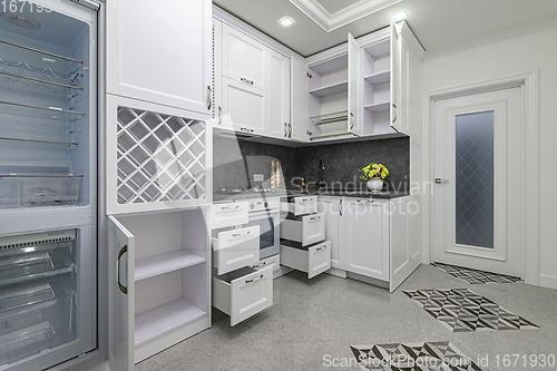 Image of Open doors and drawers open at modern white kitchen