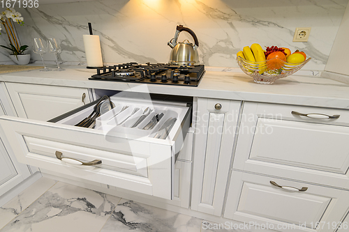 Image of Open drawer with cutlery at modern white woden kitchen in classic style