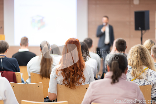 Image of Speaker giving a talk in conference hall at business event. Rear view of unrecognizable people in audience at the conference hall. Business and entrepreneurship concept.