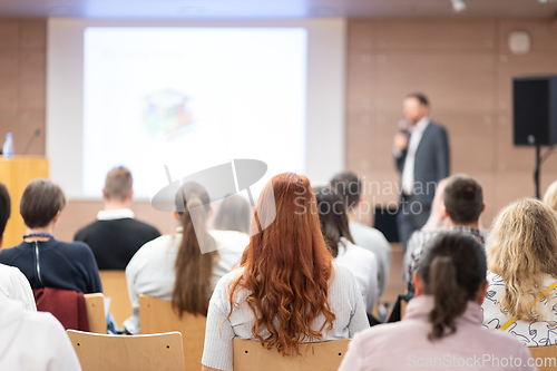 Image of Speaker giving a talk in conference hall at business event. Rear view of unrecognizable people in audience at the conference hall. Business and entrepreneurship concept.