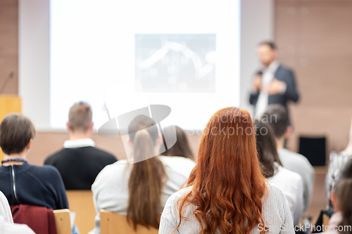 Image of Speaker giving a talk in conference hall at business event. Rear view of unrecognizable people in audience at the conference hall. Business and entrepreneurship concept.