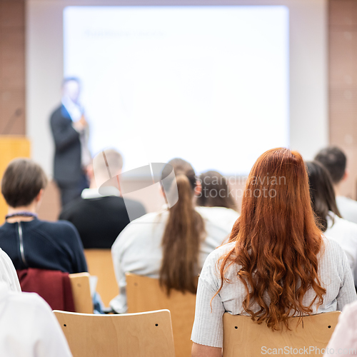 Image of Speaker giving a talk in conference hall at business event. Rear view of unrecognizable people in audience at the conference hall. Business and entrepreneurship concept.