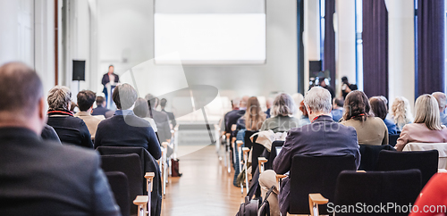 Image of Speaker giving a talk in conference hall at business event. Rear view of unrecognizable people in audience at the conference hall. Business and entrepreneurship concept.