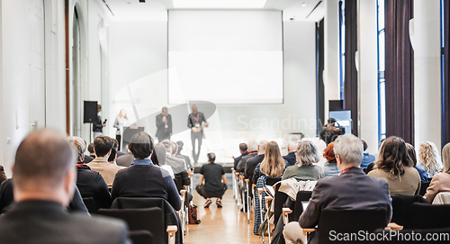 Image of Business team leader receiving award prize at best business project competition event. Business and entrepreneurship award ceremony theme. Focus on unrecognizable people in audience.