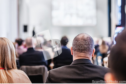 Image of Speaker giving a talk in conference hall at business event. Rear view of unrecognizable people in audience at the conference hall. Business and entrepreneurship concept.