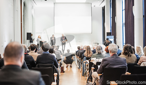 Image of Business team leader receiving award prize at best business project competition event. Business and entrepreneurship award ceremony theme. Focus on unrecognizable people in audience.