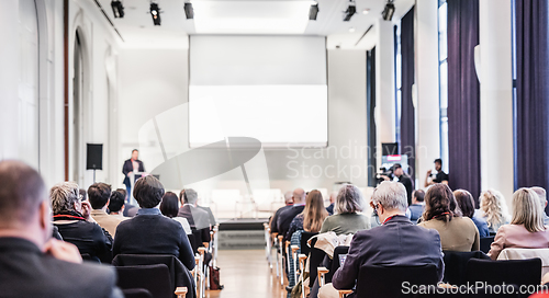 Image of Speaker giving a talk in conference hall at business event. Rear view of unrecognizable people in audience at the conference hall. Business and entrepreneurship concept.