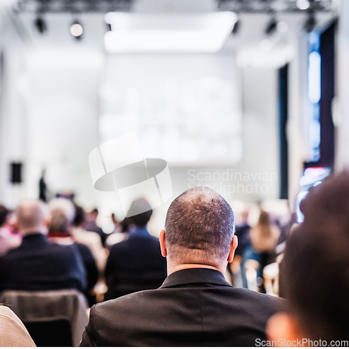 Image of Speaker giving a talk in conference hall at business event. Rear view of unrecognizable people in audience at the conference hall. Business and entrepreneurship concept.