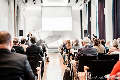 Image of Speaker giving a talk in conference hall at business event. Rear view of unrecognizable people in audience at the conference hall. Business and entrepreneurship concept.